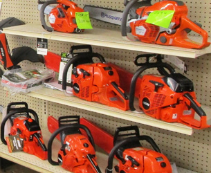 Several red chainsaws on a pegboard wall