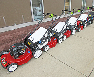 A row of red Toro walk-behind lawn mowers